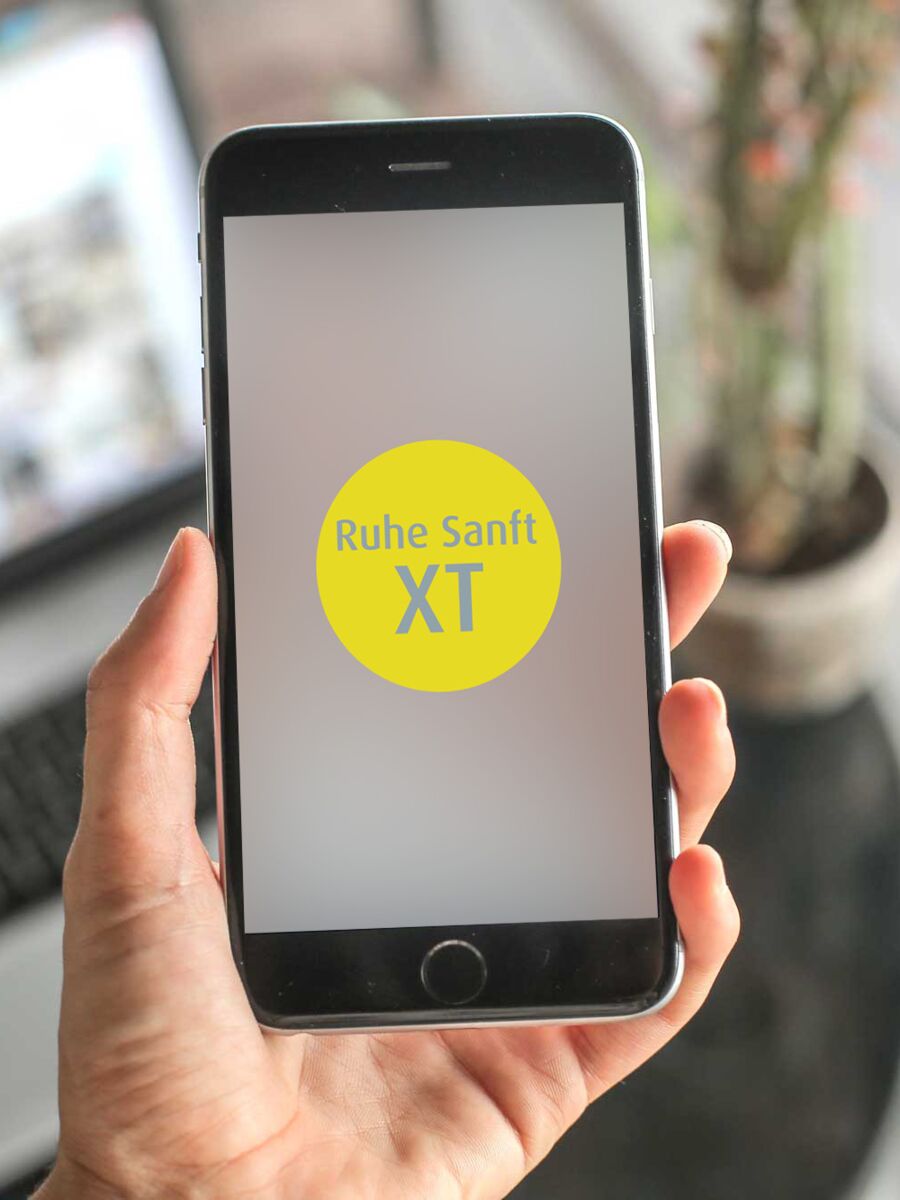 Im Vordergrund ein Smartphone mit dem Ruhe Sanft XT-Schriftzug  auf dem Display, im Hintergrund ein Laptop